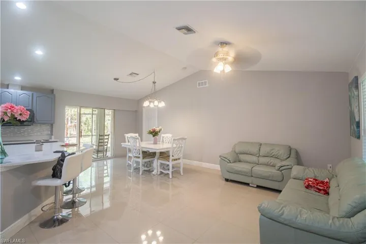 Living area featuring baseboards, lofted ceiling, light tile patterned flooring, recessed lighting, and a ceiling fan