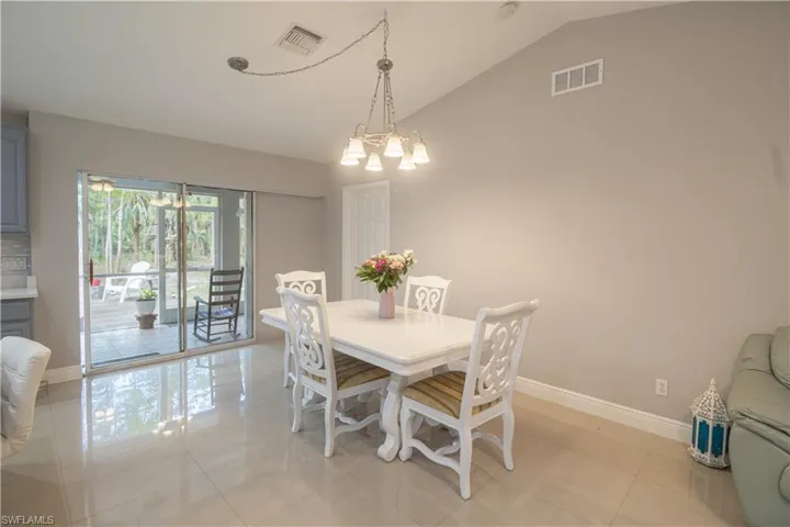 Dining area with vaulted ceiling, baseboards, light tile patterned flooring, and a chandelier