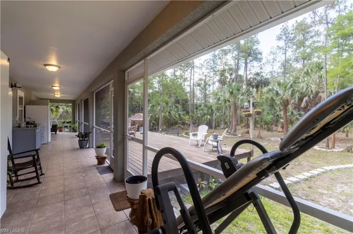 View of patio / terrace featuring a sunroom and view of wooded area