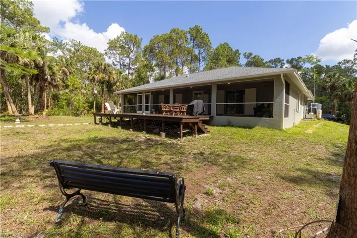 Rear view of property featuring a yard, stucco siding, and a wooden deck