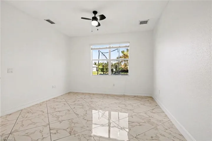 Empty room featuring light marble finish floors and ceiling fan