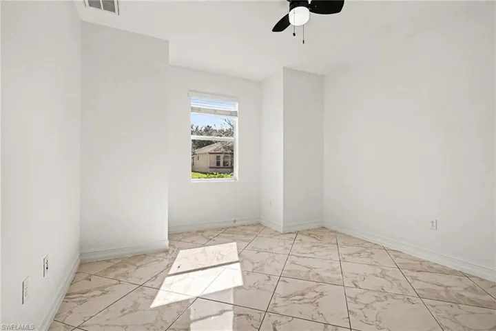 Spare room with light marble finish flooring and a ceiling fan