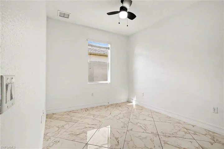 Spare room featuring light marble finish floors and a ceiling fan