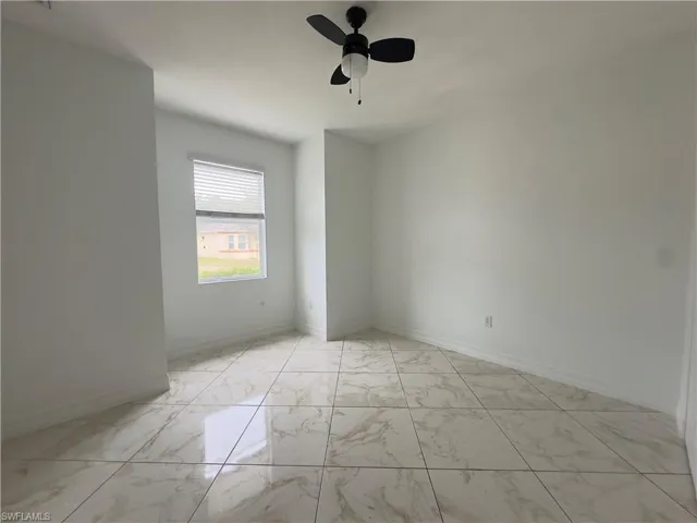 Unfurnished room featuring a water view, ceiling fan, and light marble finish floors