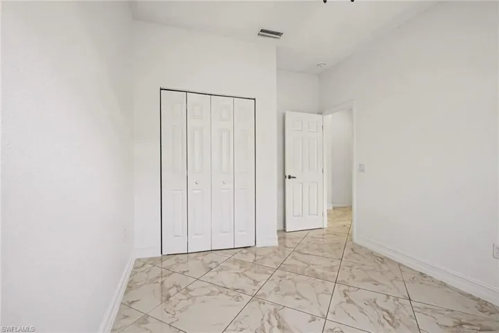 Unfurnished bedroom with light marble finish floors and a closet