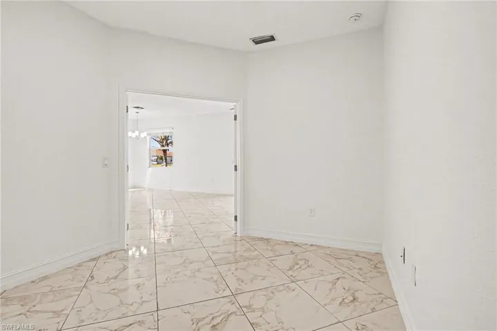 Spare room with light marble finish flooring and a chandelier