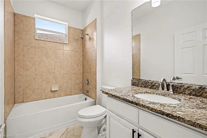 Full bath with vanity, shower / tub combination, and a textured wall