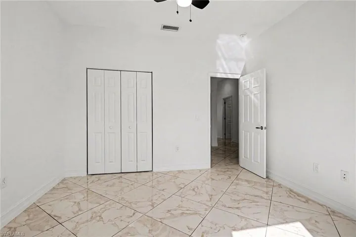 Unfurnished bedroom with a closet, light marble finish floors, and a ceiling fan
