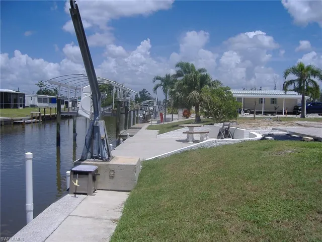 Dock area featuring a lawn, boat lift, and a water view