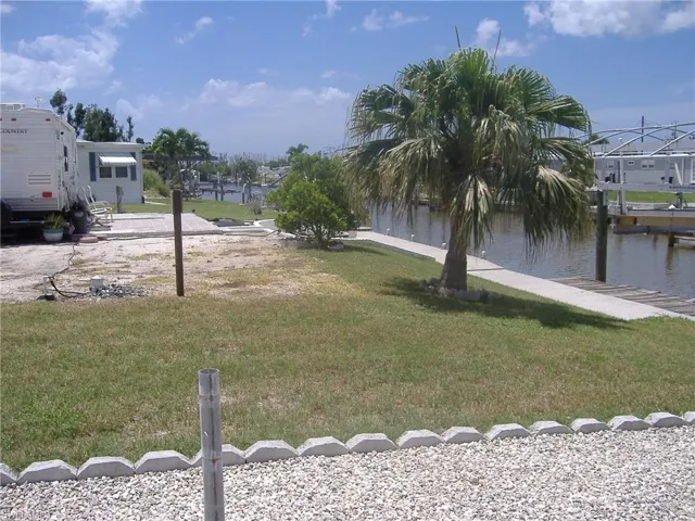 View of grassy yard featuring a water view and a boat dock