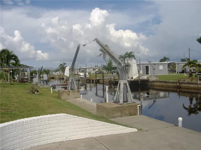 Dock area featuring boat lift, a lawn, and a water view