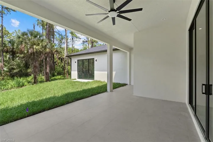 Expansive covered patio with a ceiling fan and recessed lighting, featuring large format floor tiles and sliding glass doors