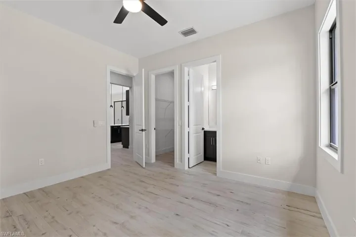 Light wood-finish flooring, ceiling fan, white trim, and multiple doorways