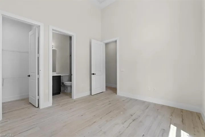 Vaulted ceiling, light wood-finish flooring, white walls, and white interior doors with black hardware