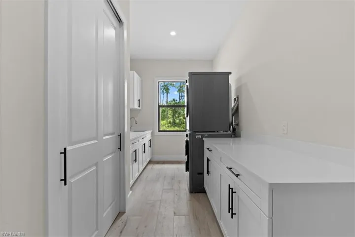 Built-in cabinetry with matte black hardware, white countertops, wood-finish flooring, and a large window