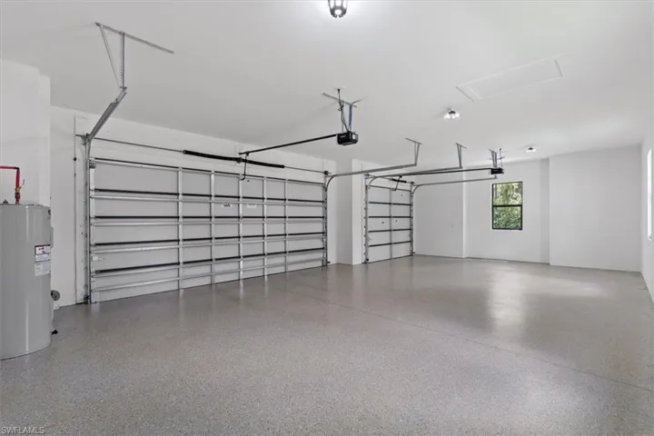 Two garage doors with automatic openers, sealed concrete flooring, recessed lighting, and a single window