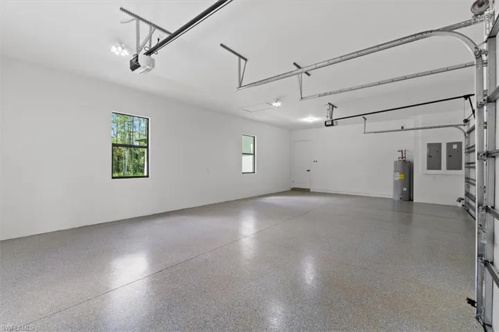 Spacious garage featuring a finished epoxy floor, two windows, and overhead lighting