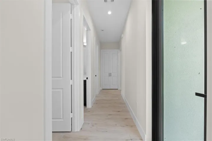 Recessed lighting, light wood-finish flooring, white walls, white paneled doors, and a full-lite privacy glass door