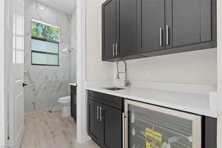 Built-in cabinetry with stainless steel hardware, white countertop, and integrated beverage cooler