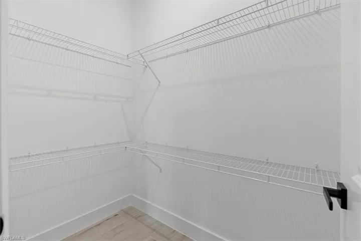 Corner closet with multi-level wire shelving and wood-finish flooring