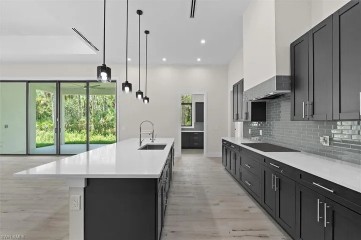 Kitchen featuring an oversized island, white countertops, dark cabinetry, and wood-finish flooring