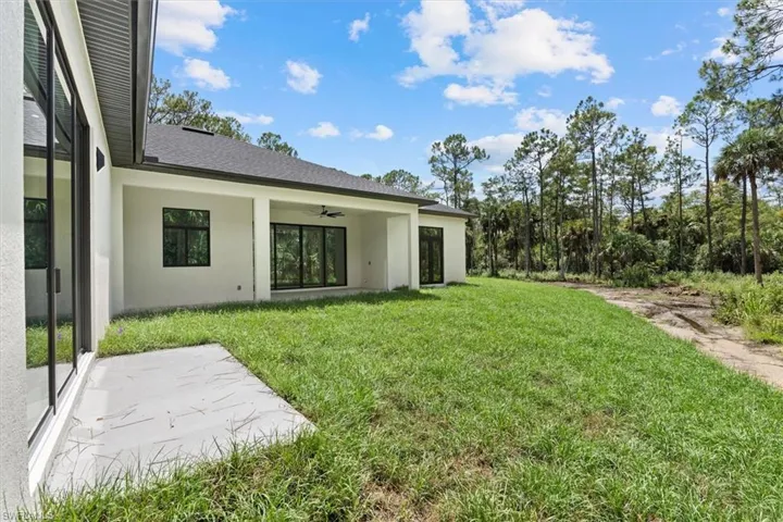 Expansive backyard featuring a manicured lawn, an extended patio, and a covered lanai with a ceiling fan