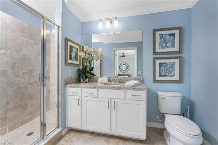 Full bathroom with tile patterned floors, a stall shower, toilet, and crown molding