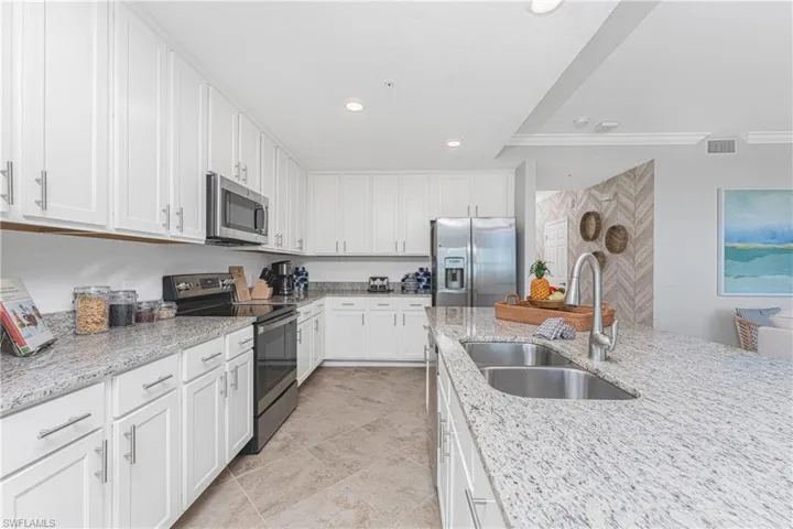 Kitchen with visible vents, a sink, white cabinetry, appliances with stainless steel finishes, and light stone countertops