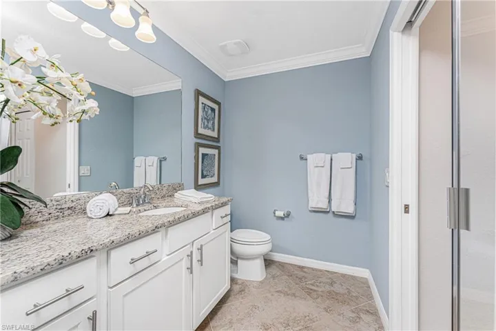 Bathroom with toilet, vanity, baseboards, and ornamental molding