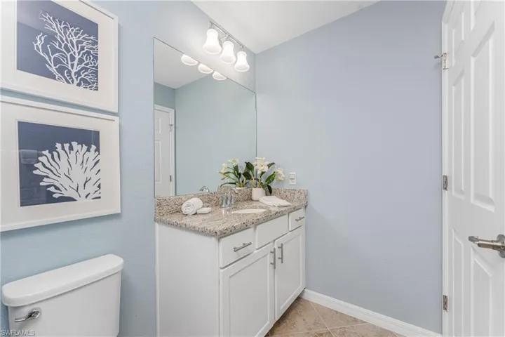 Bathroom featuring tile patterned floors, baseboards, toilet, and vanity