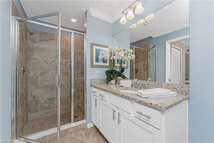 Full bath featuring a stall shower, vanity, and crown molding