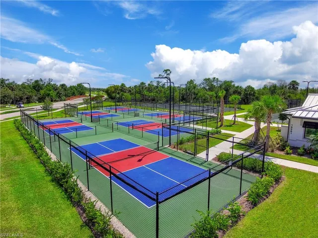 View of tennis court featuring a lawn and fence