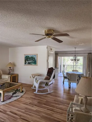 Living area with ceiling fan, wood finished floors, a textured ceiling, and a chandelier