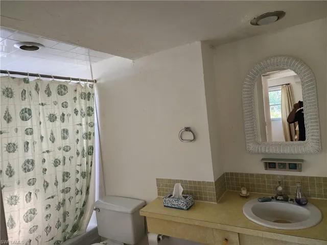 Bathroom featuring vanity, shower / bath combo, and backsplash