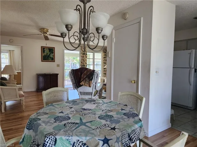Dining area with a chandelier, a textured ceiling, wood finished floors, and ceiling fan