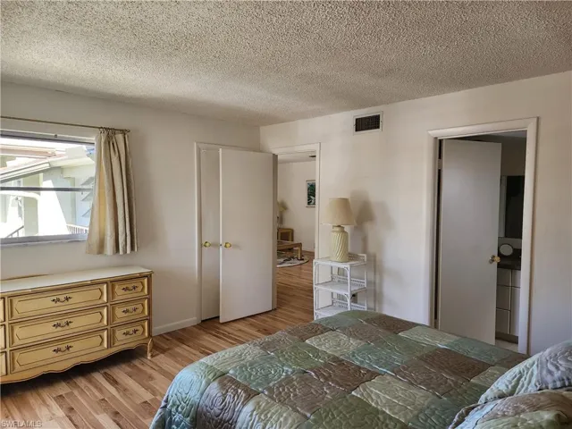 Bedroom with light wood finished floors and a textured ceiling