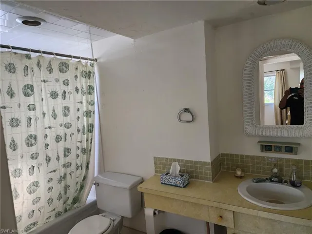 Full bath featuring shower / tub combo, vanity, and decorative backsplash