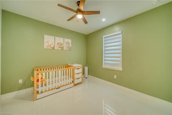 Bedroom featuring a crib, a ceiling fan, and light tile patterned flooring