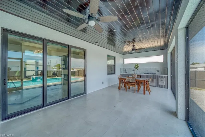Sunroom / solarium featuring outdoor dining space, a ceiling fan, and a patio