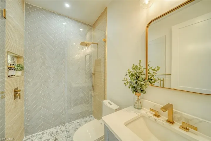 Bathroom featuring a tile shower, vanity, and recessed lighting
