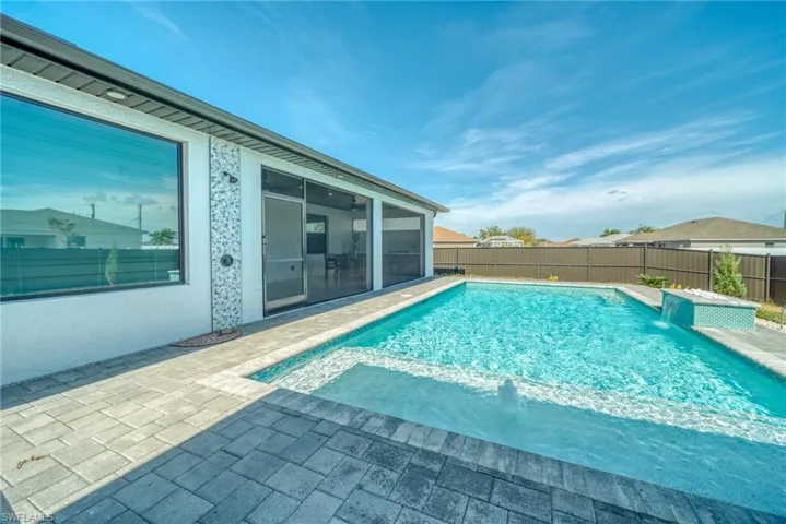 View of swimming pool with a sunroom, a fenced backyard, and patio surround