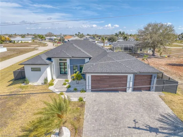 View of front of house featuring an attached garage, stucco siding, driveway, a shingled roof, and a residential view