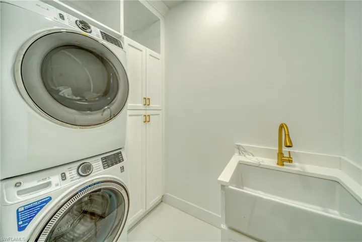 Laundry area featuring stacked washer / dryer, cabinet space, and pantry