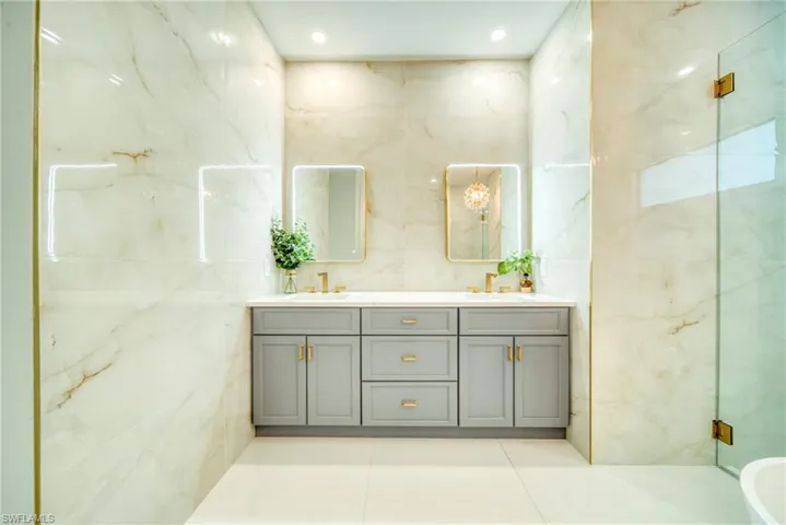 Full bathroom with double vanity and tile walls
