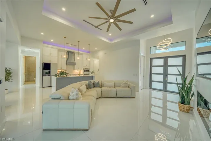 Living area featuring a ceiling fan, french doors, light tile patterned floors, recessed lighting, and a tray ceiling