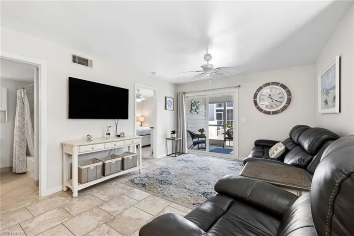 Living area featuring neutral-toned tile flooring, recessed lighting, a white ceiling fan, and sliding glass doors