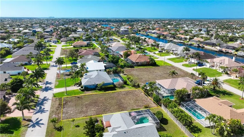 Aerial view of residential area with property parcel outlined and a nearby body of water