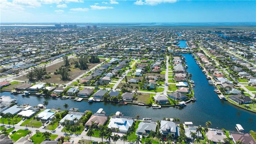 Aerial view of property and surrounding area featuring a nearby body of water and nearby suburban area