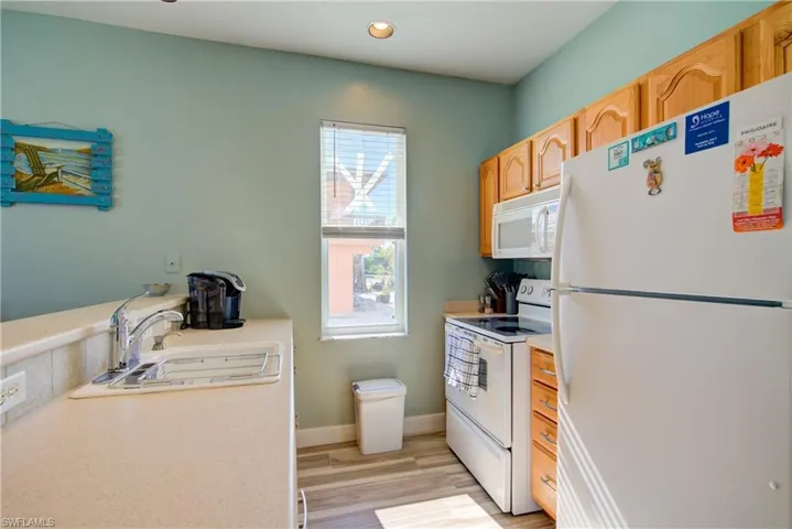 Kitchen with white appliances, light countertops, light wood-type flooring, light brown cabinets, and recessed lighting