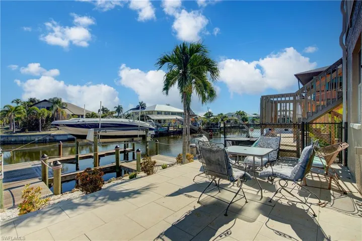Dock area with boat lift, a water view, outdoor dining area, and stairs